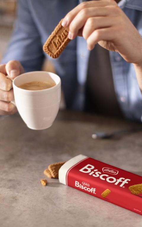 A cup of coffee holding a biscoff cookie