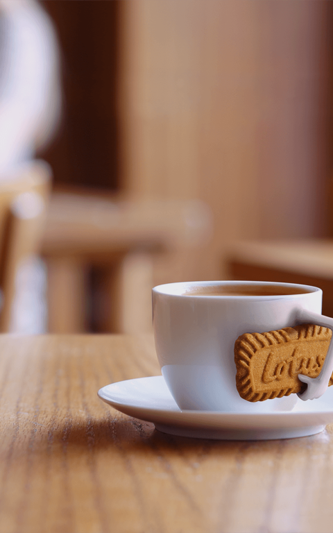 A cup of coffee holding a Biscoff® cookie